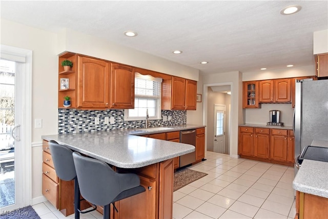 kitchen with stainless steel appliances, a peninsula, and brown cabinetry