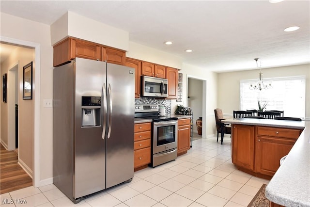 kitchen with tasteful backsplash, an inviting chandelier, light tile patterned floors, stainless steel appliances, and hanging light fixtures