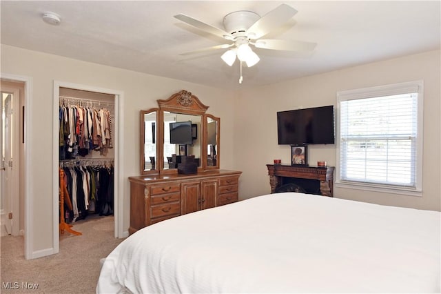 bedroom with a closet, a spacious closet, ceiling fan, and light carpet