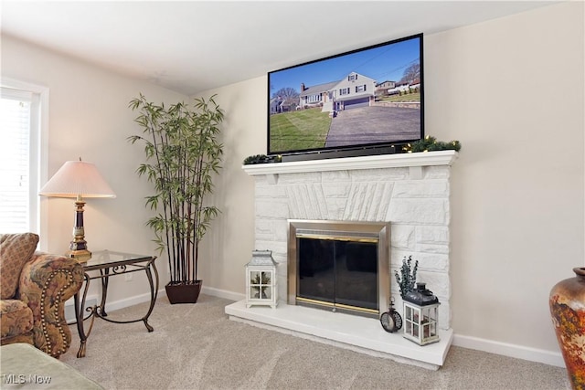 living area featuring carpet floors, a stone fireplace, and baseboards