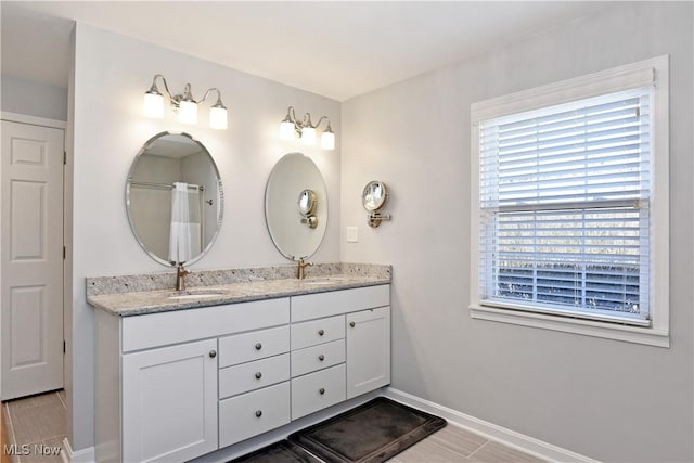 full bathroom featuring a sink, baseboards, and double vanity