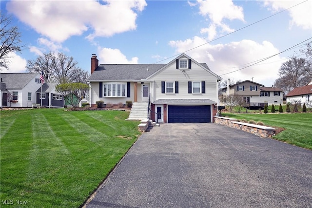 tri-level home with a garage, a chimney, a front lawn, a residential view, and driveway