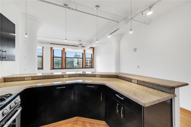 2077 E 4th St E Unit 4E, Cleveland, OH 44115 - kitchen featuring light stone countertops, dark cabinets, track lighting, light wood-style flooring, and stainless steel gas range