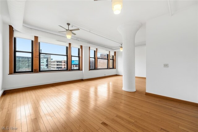 2077 E 4th St E Unit 4E, Cleveland, OH 44115 - empty room featuring ceiling fan, ornate columns, light wood-style floors, and baseboards