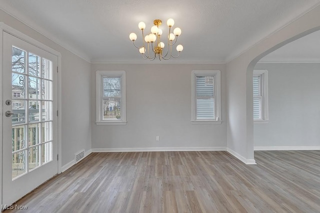 unfurnished room with visible vents, baseboards, an inviting chandelier, and wood finished floors