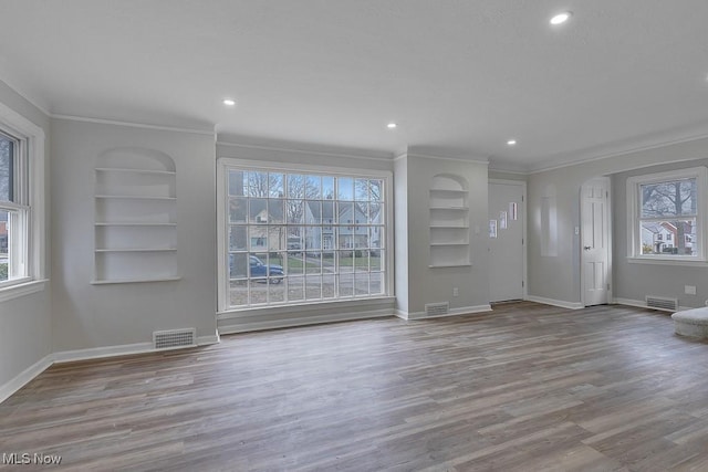 unfurnished living room featuring built in shelves, visible vents, and baseboards