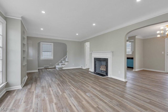 unfurnished living room with visible vents, arched walkways, wood finished floors, and a fireplace