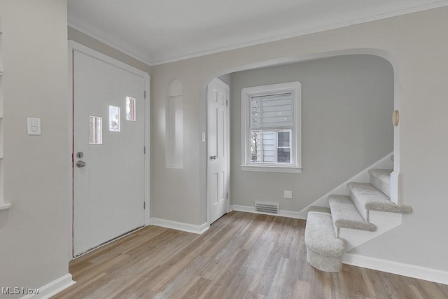 foyer featuring arched walkways, wood finished floors, baseboards, and visible vents