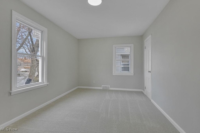 carpeted empty room with a wealth of natural light, visible vents, and baseboards