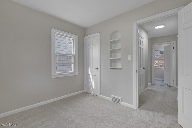 unfurnished bedroom with visible vents, baseboards, and light carpet