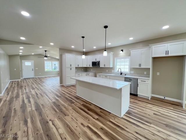kitchen with a kitchen island, white cabinetry, stainless steel appliances, and a sink