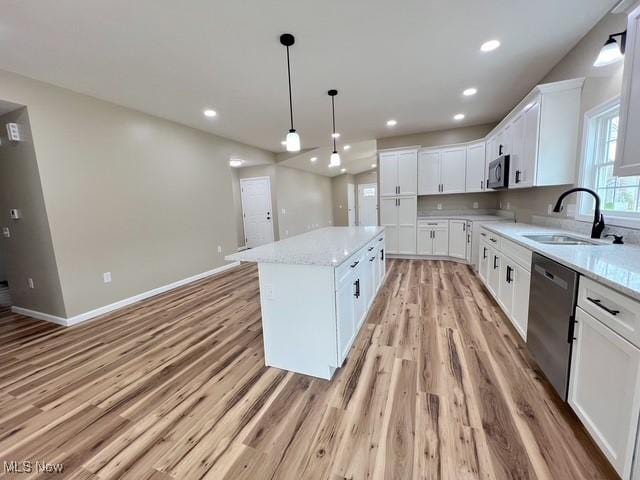kitchen featuring a sink, a kitchen island, stainless steel appliances, white cabinets, and light wood-type flooring