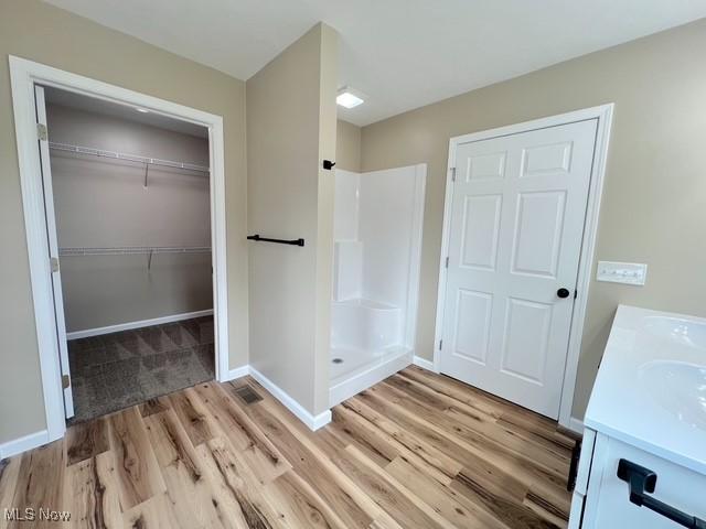 bathroom featuring a stall shower, baseboards, vanity, and wood finished floors