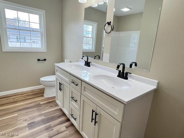 full bath featuring double vanity, wood finished floors, baseboards, and a sink