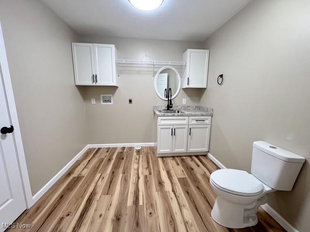 laundry room featuring a sink, laundry area, light wood-style flooring, baseboards, and hookup for a washing machine