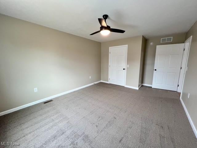 unfurnished bedroom with ceiling fan, baseboards, visible vents, and dark carpet