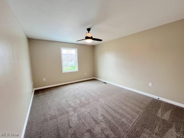 carpeted empty room featuring ceiling fan and baseboards
