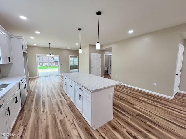 kitchen with light wood finished floors, baseboards, a center island, and white cabinets