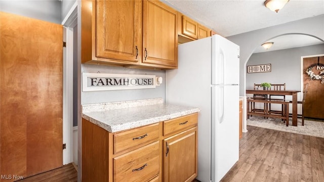 3020 State Route 376, Stockport, OH 43787 - kitchen featuring arched walkways, light stone countertops, freestanding refrigerator, and wood finished floors