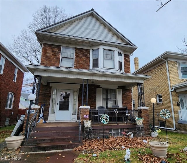 american foursquare style home featuring a porch and brick siding