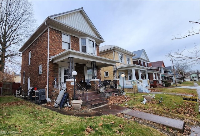 traditional style home featuring brick siding, a front lawn, and covered porch