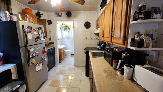 kitchen featuring freestanding refrigerator, light tile patterned floors, black dishwasher, a sink, and brown cabinets