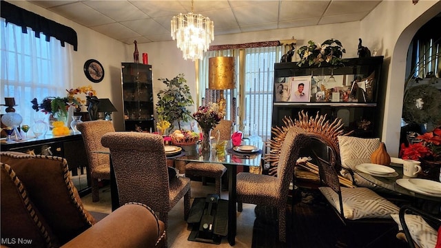 dining room with arched walkways, a paneled ceiling, and a chandelier