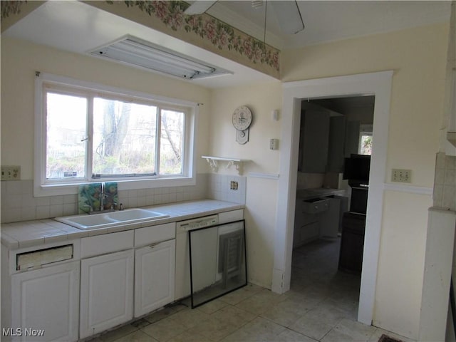 1831 Knowles St, East Cleveland, OH 44112 - kitchen featuring white dishwasher, a sink, white cabinetry, backsplash, and tile countertops