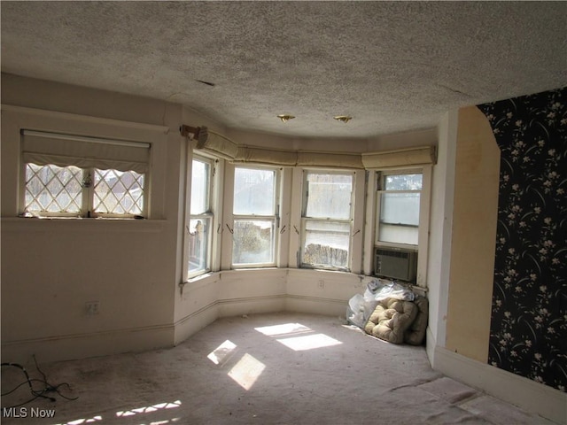 1831 Knowles St, East Cleveland, OH 44112 - spare room featuring cooling unit, a textured ceiling, wallpapered walls, and a healthy amount of sunlight