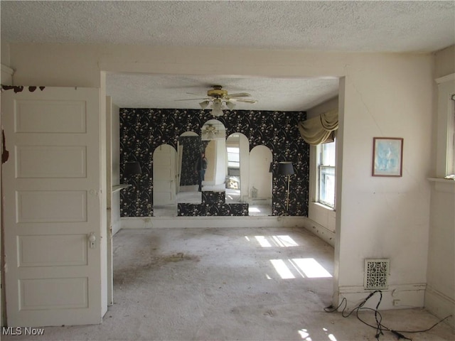 1831 Knowles St, East Cleveland, OH 44112 - unfurnished living room featuring visible vents, a textured ceiling, wallpapered walls, and ceiling fan