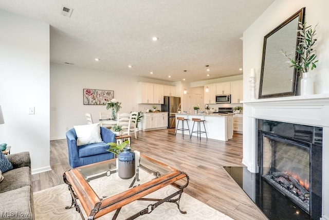 835-2 Dipper Ln, Aurora, OH 44202 - living area featuring a tiled fireplace, recessed lighting, and light wood-style floors