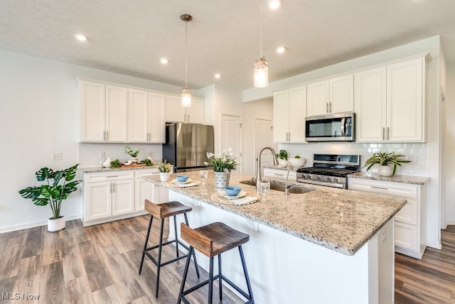835-2 Dipper Ln, Aurora, OH 44202 - kitchen featuring stainless steel appliances, wood finished floors, tasteful backsplash, an island with sink, and white cabinets