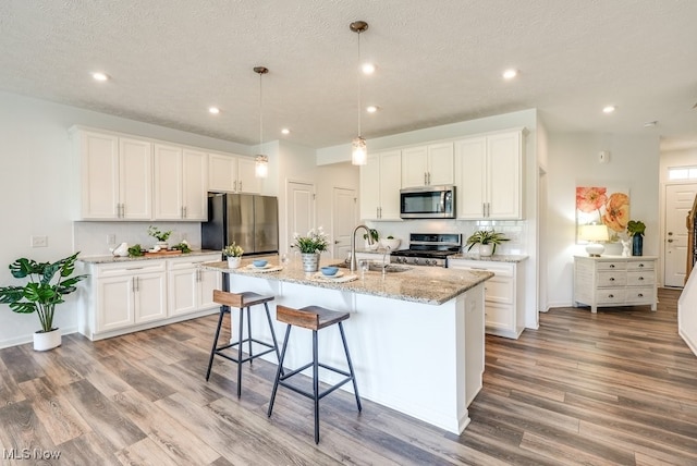 835-2 Dipper Ln, Aurora, OH 44202 - kitchen with stainless steel appliances, light wood-style flooring, an island with sink, white cabinets, and a breakfast bar
