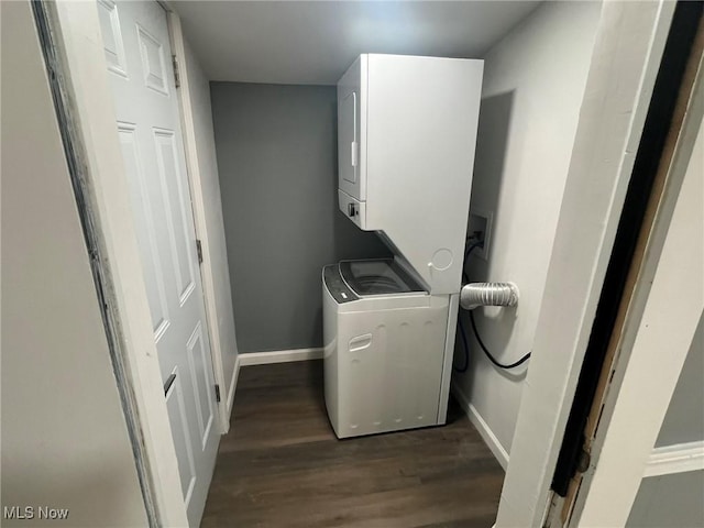 laundry area with baseboards, laundry area, wood finished floors, and stacked washer and clothes dryer
