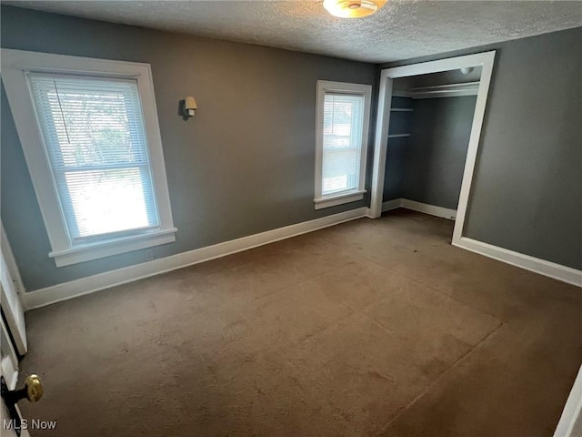 unfurnished bedroom with a closet, carpet flooring, a textured ceiling, and baseboards