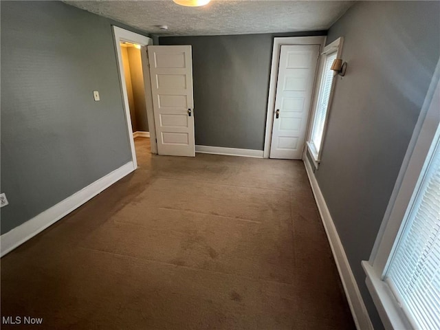 corridor with a textured ceiling, carpet flooring, and baseboards