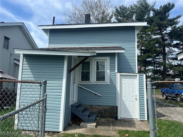rear view of house with entry steps and fence