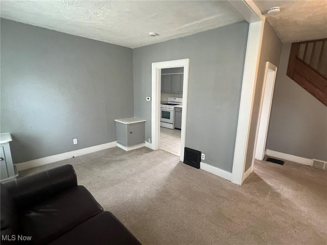 carpeted living area with visible vents, baseboards, and a textured ceiling