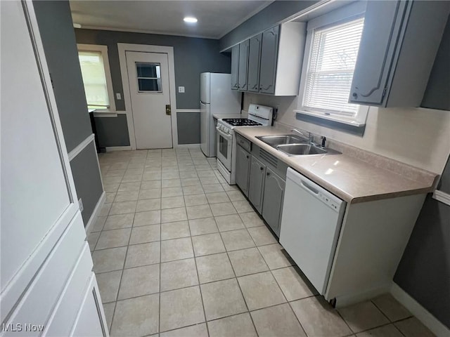 kitchen featuring white appliances, gray cabinets, a sink, and light tile patterned flooring
