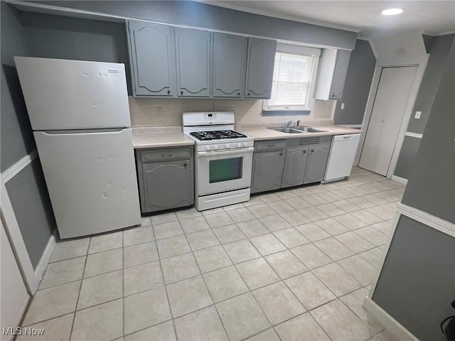 kitchen with gray cabinets, white appliances, light countertops, light tile patterned flooring, and a sink