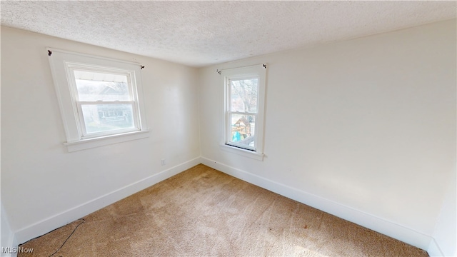 unfurnished room with baseboards, light carpet, and a textured ceiling