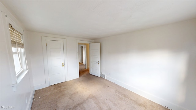 unfurnished bedroom with carpet flooring, baseboards, and visible vents