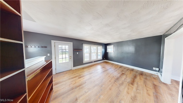 unfurnished living room with baseboards, a wall mounted AC, and wood finished floors