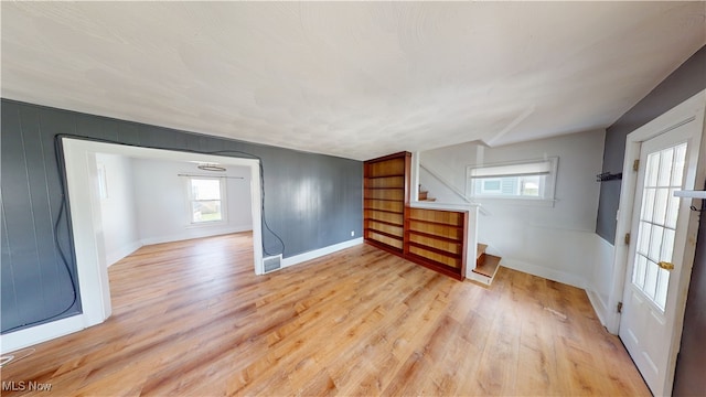 spare room with light wood-style flooring, baseboards, visible vents, and stairs