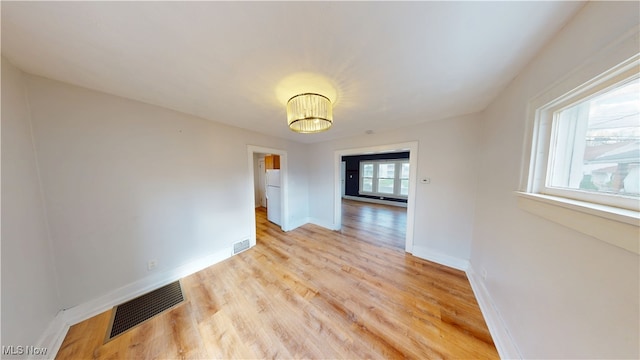 spare room featuring visible vents, baseboards, and light wood finished floors