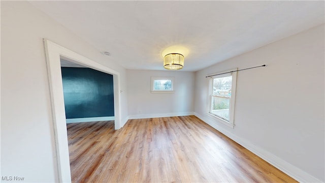 unfurnished room with light wood-style flooring and baseboards