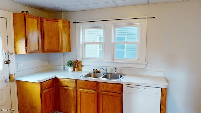 kitchen with white dishwasher, a sink, light countertops, a paneled ceiling, and brown cabinets