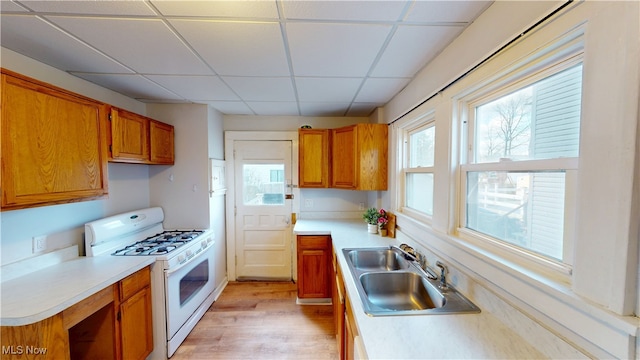 kitchen featuring a sink, brown cabinetry, plenty of natural light, and gas range gas stove