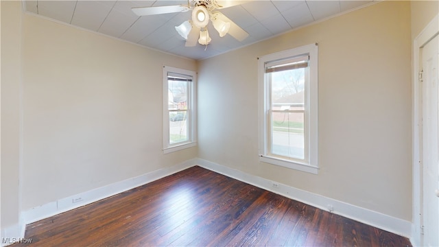 unfurnished room featuring crown molding, baseboards, plenty of natural light, and dark wood finished floors