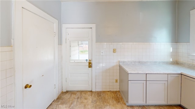 kitchen with gray cabinetry, light countertops, wainscoting, and tile walls